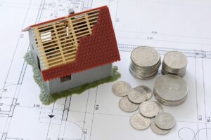 Esta imagem tem a miniatura de uma casa e dinheiro do lado, simbolizando uma operação Home Equity, ou Crédito com Garantia de Imóvel.