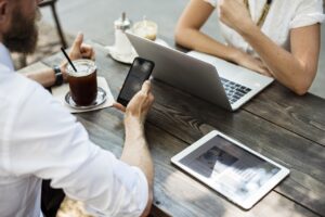 Imagem com empresários trabalhando com celular e computador, ilustrando o simulador de crédito online para empresários que a 4TE Group lançou.